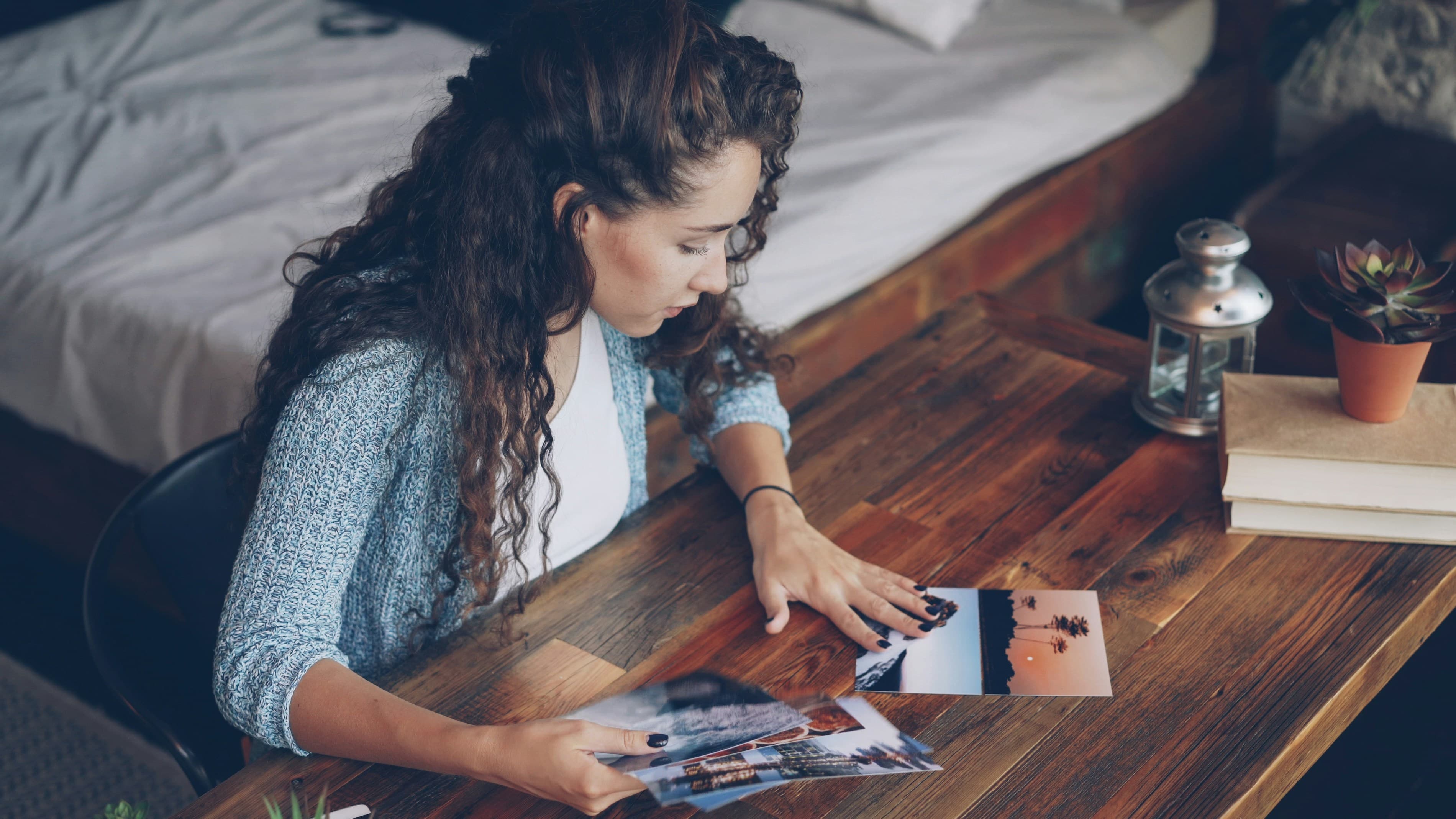 Young woman looking through family photographs on a wooden table