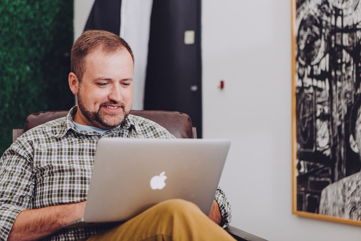Man smiling while reviewing content on his laptop, engaged and satisfied